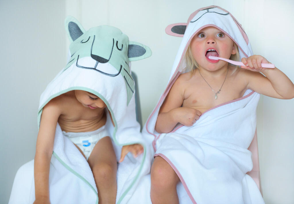 To barn med hettehåndkle på seg og pusser tenner. Bilde