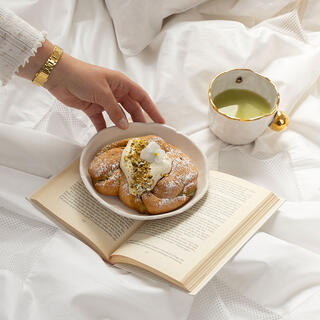Frokost på senga servert på brett med en bok og lesebriller. Bilde