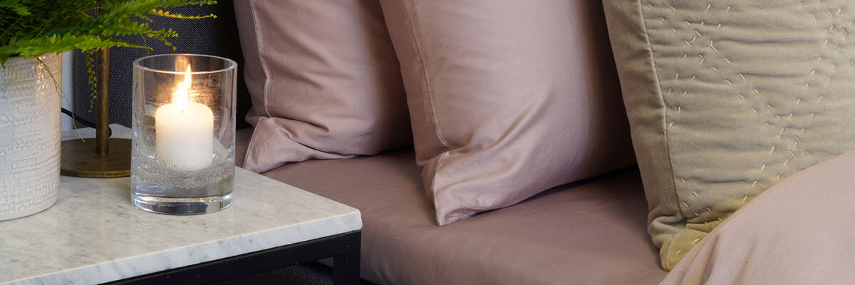 Konvoluttlaken fra Borås Cotton ferdig oppredd på seng i fargen dusty pink.